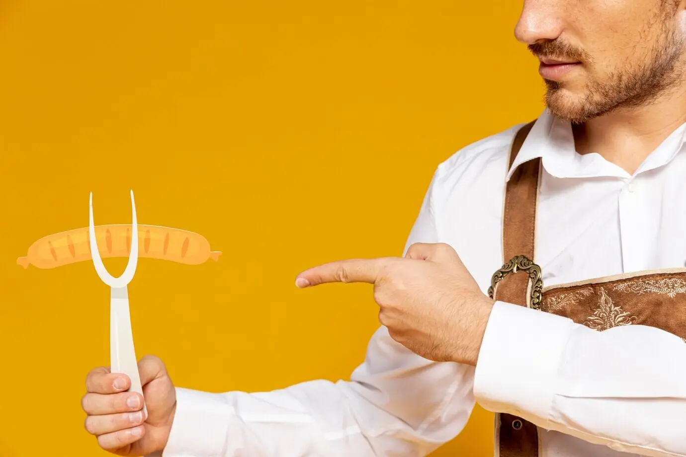 Ein Mann zeigt auf eine Nachbildung einer deutschen Wurst.