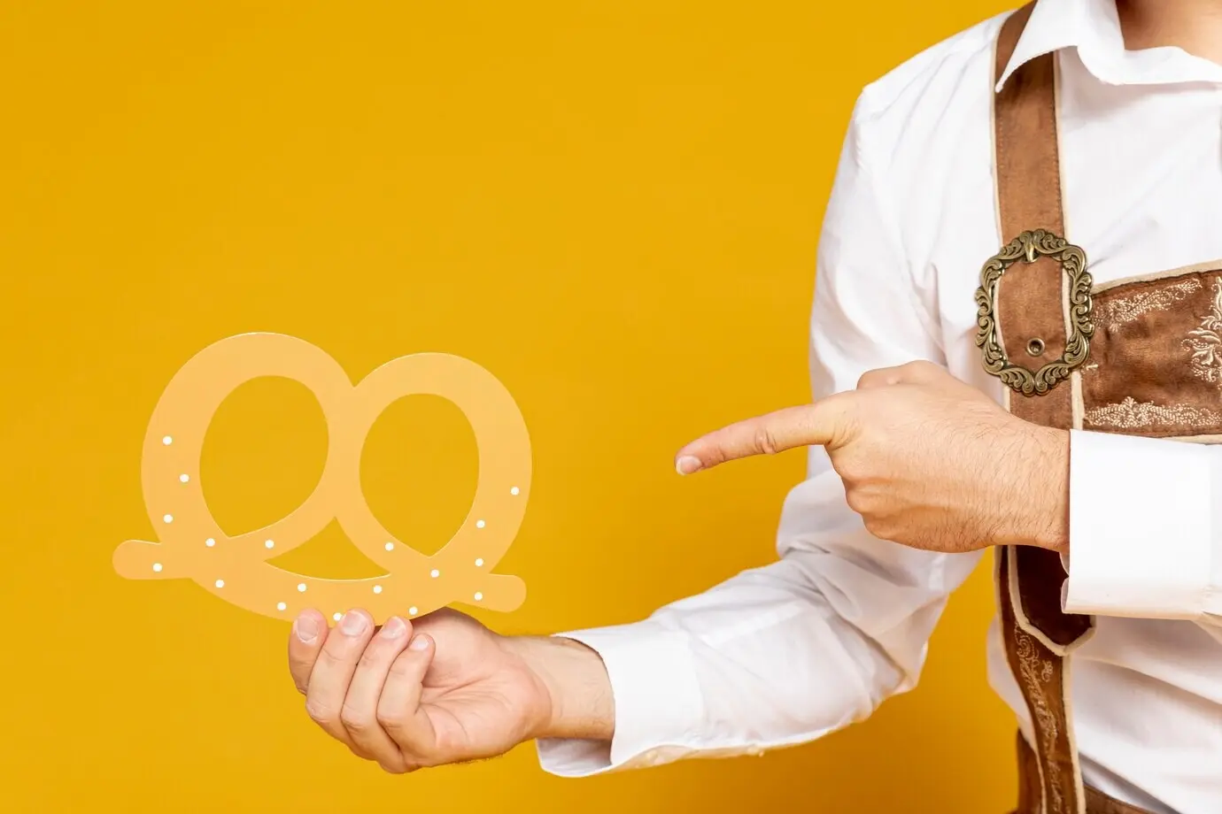 Ein Mann zeigt auf eine Brezel-Nachbildung.